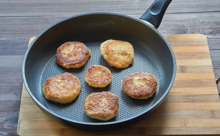 fried curd cottage cheese pancakes in frying pan, close upの写真素材