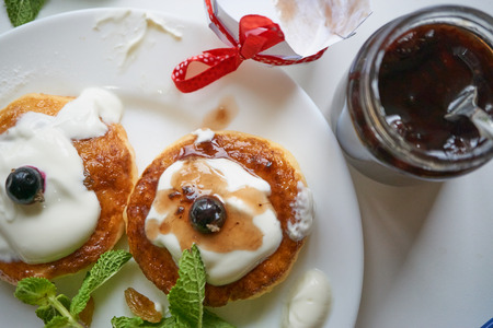curd cottage cheese pancakes on white plate with raisins, mint and currant berries. opened jar with jam. close up macro shot from the top. high angle shotの写真素材