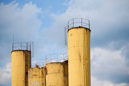 vivid yellow storage pipes of the abandoned factory against the blue skyの写真素材