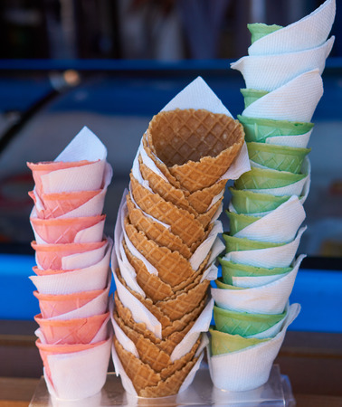three stacks of empty sugar vivid multi-colored wafer cone cups for ice cream. pink, green and chocolateの写真素材