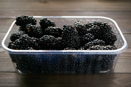 fresh tasty blackberry in a plastic transparent tray on dark table. low angle shotの写真素材