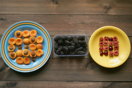 macro pattern from apricots and cherries on a plates and basket with blackberry. top view. apricots with cherries cut in a halfの写真素材