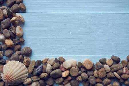 corner frame from pebbles stones rocks and seashell on light blue surface wooden desk. great for summer vacation photo videoの写真素材
