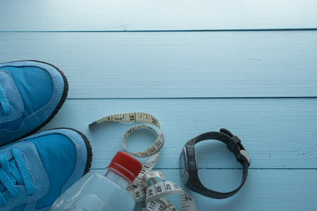 sport stopwatch, water bottle, ruler measuring tape and blue pair of sport sneakers on blue wooden background. top angle viewの写真素材