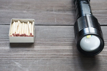 box of matches and flashlight on a wooden desk. old versus modern concept. low angle shotの写真素材