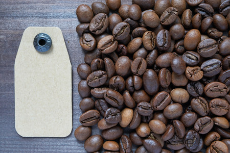 cardboard tag near coffee beans on dark background. label for different sorts of coffeeの写真素材