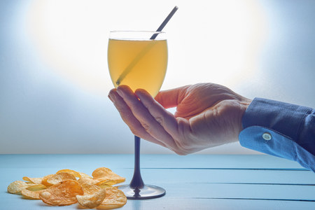 barman hand with cocktail drink with straw and potato crisps on a desk