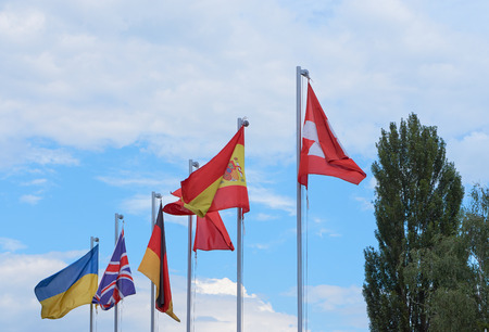 a group of european country flags waving on flag poles against blue sky. flags of Ukraine, Great Britain, Germany, Spain, Switzerland. with copy spaceの写真素材