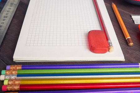 school notepad with colorful pencils, eraser and ruler aside
