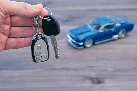 hand with car keys and small toy car model blurred on background. concept image for rent or buy a carの写真素材