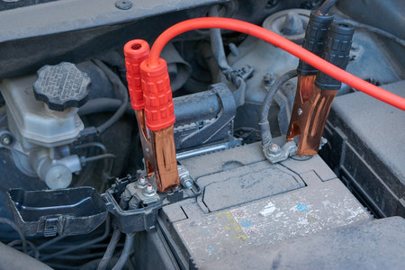 jump start charging automobile battery with another car jumper cables at cold winter. discharged low...