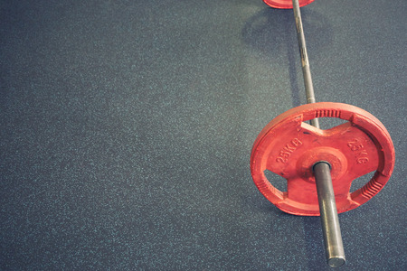barbell with vivid red weights lay on floor in gym. high angle shot with lot of copy spaceの写真素材