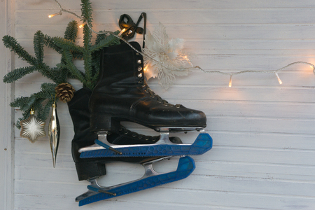 black skates with spruce branch hanging on the wall. christmas toys decoration and garlands lights sparkling. perfectly describe Christmas atmosphereの写真素材
