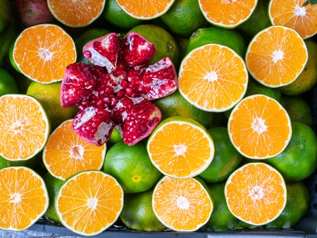 large peeled pomegranate among cutted in a half oranges lemons with green skin, flat lay top viewの写真素材