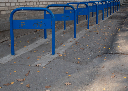 empty parking bike slots at the street. row of blue pipes with bicycle and parking signsの写真素材
