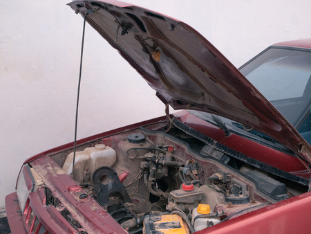 opened car hood with visible parts but without engine. mechanic fix, repair, service concept. side outdoor shotの写真素材