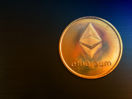 one ethereum gold coin on black metal surface as background. low key flat lay shotの写真素材