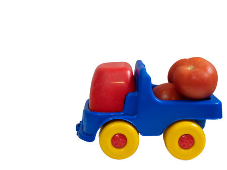 colorful vivid toy car truck with red tomatoes. side shot cutout isolated on white backgroundの写真素材