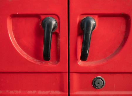 closeup of two closed doors red car minivan cargo turning handles and keyholeの写真素材