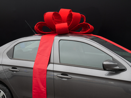 gray car with red ribbon on dark black background. perfect gift presentの写真素材