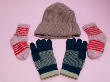 set of winter must have cloth accessories - woolen hat, gloves and socks. on pink backgroundの写真素材