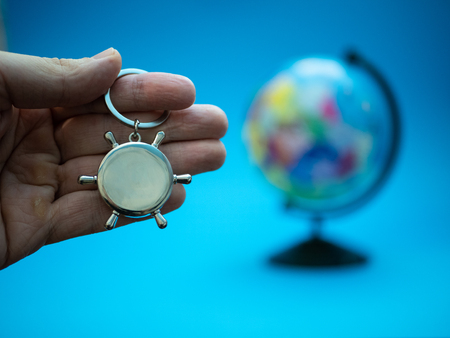 hand with naval ship steering wheel and globe blurred on background, selective focus on foreground. overseas global delivery business conceptの写真素材