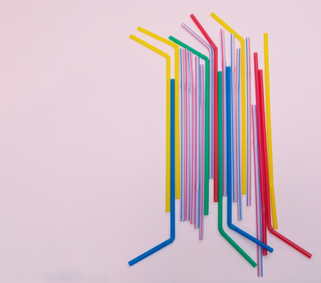 lot of different colorful vivid drink straws on pink background. flat lay image