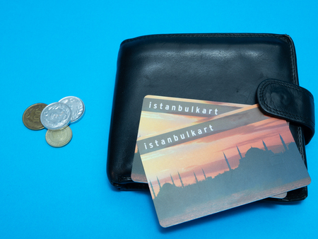black wallet with Istanbulkart transportation Istanbul plastic card and Turkish liras coins on blue backgroundの写真素材