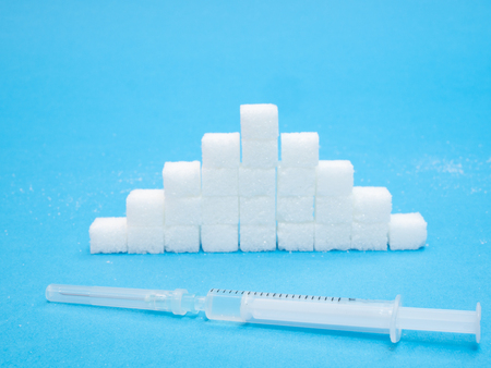 pile of white blocks of sugar and syringe with insulin. blood glucose level quality conceptの写真素材