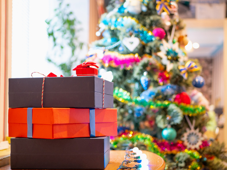 few gift presents boxes near Christmas tree blurred on background. selective focus on boxes. indoor closeup imageの写真素材
