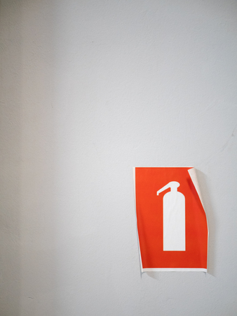 peeling off orange fire extinguisher sign sticker on white light wallの写真素材