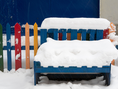 closeup of wooden bench under huge snowdrift. vivid colorful outdoor shot made at snowstormの写真素材