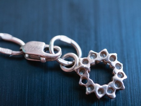 close-up macro image of silver pendant in shape of sun on polished metalic black surfaceの写真素材