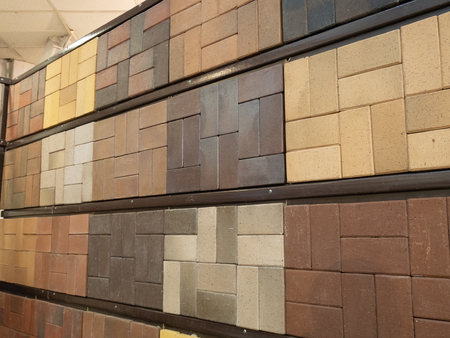 wall made of different samples of sidewalk pavement bricks tiles. various colors and patterns....