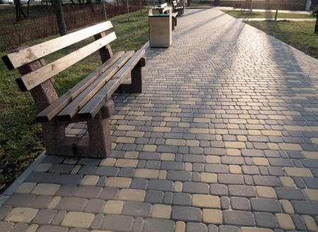 empty alley with bench and cobblestone sidewalk at city park at sunsetの写真素材