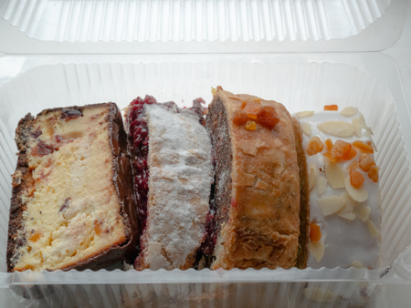 closeup of four pieces of different cakes in transparent plastic disposable containerの写真素材