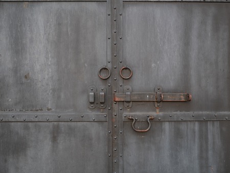 closed vintage retro black rusty metallic iron doors with bolt and round handlesの写真素材
