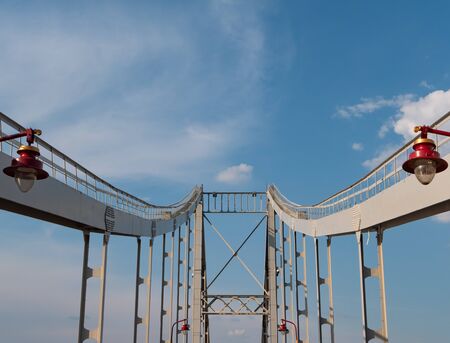 iron bridge with red modern city lanterns. deep perspective, bridge columns leads to blue sky on background.の写真素材