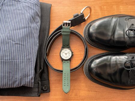 top view on businessman clothing set - pants, shirt, pair of black shoes, wrist watch and leather...
