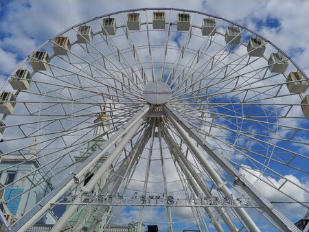 huge Ferris wheel at city center. entertainment for adults and children. blue sky with clouds on background. low angle imageの写真素材