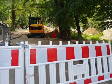 fence at construction site with piles of ground and excavator on backgroundの写真素材
