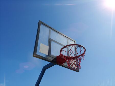 side view of basketball ring basket outdoor with clear blue sky on background and bright sun at...
