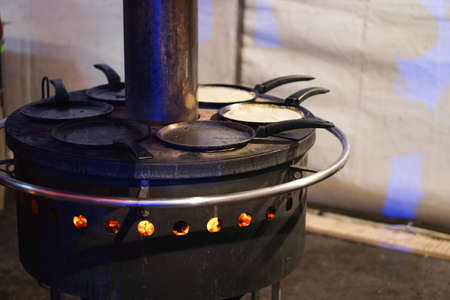 industrial traditional open fire pancake maker for few frying pans at ukrainian bazaar. High quality photoの写真素材