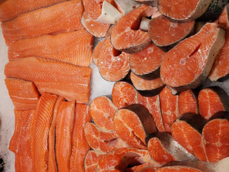 fresh raw red salmon fish steaks and fillet on ice at market counter . close-up photo