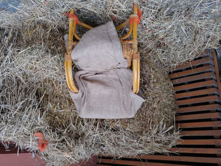 wooden wicker chair covered with rug near pile of hay stacks. farmers place for restの写真素材