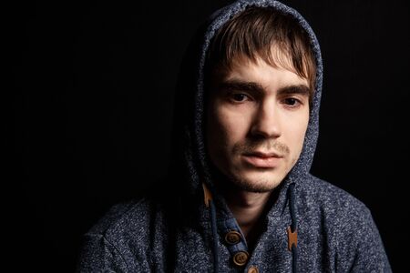 Portrait of a sad helpless man on black background looking downの写真素材