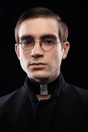 Close up portrait of handsome young catholic priest looking straight