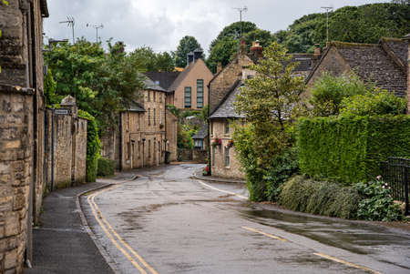 Narrow streets of a small village after rain with visible puddles on the pavement, Surrey, UK.