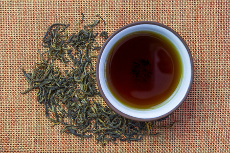 A cup of tea and teapot, tea poured in bulkの写真素材
