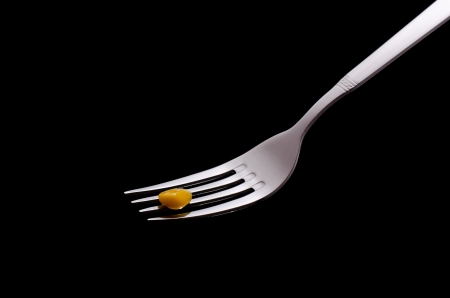 Fork with corn grain on a black backgroundの写真素材